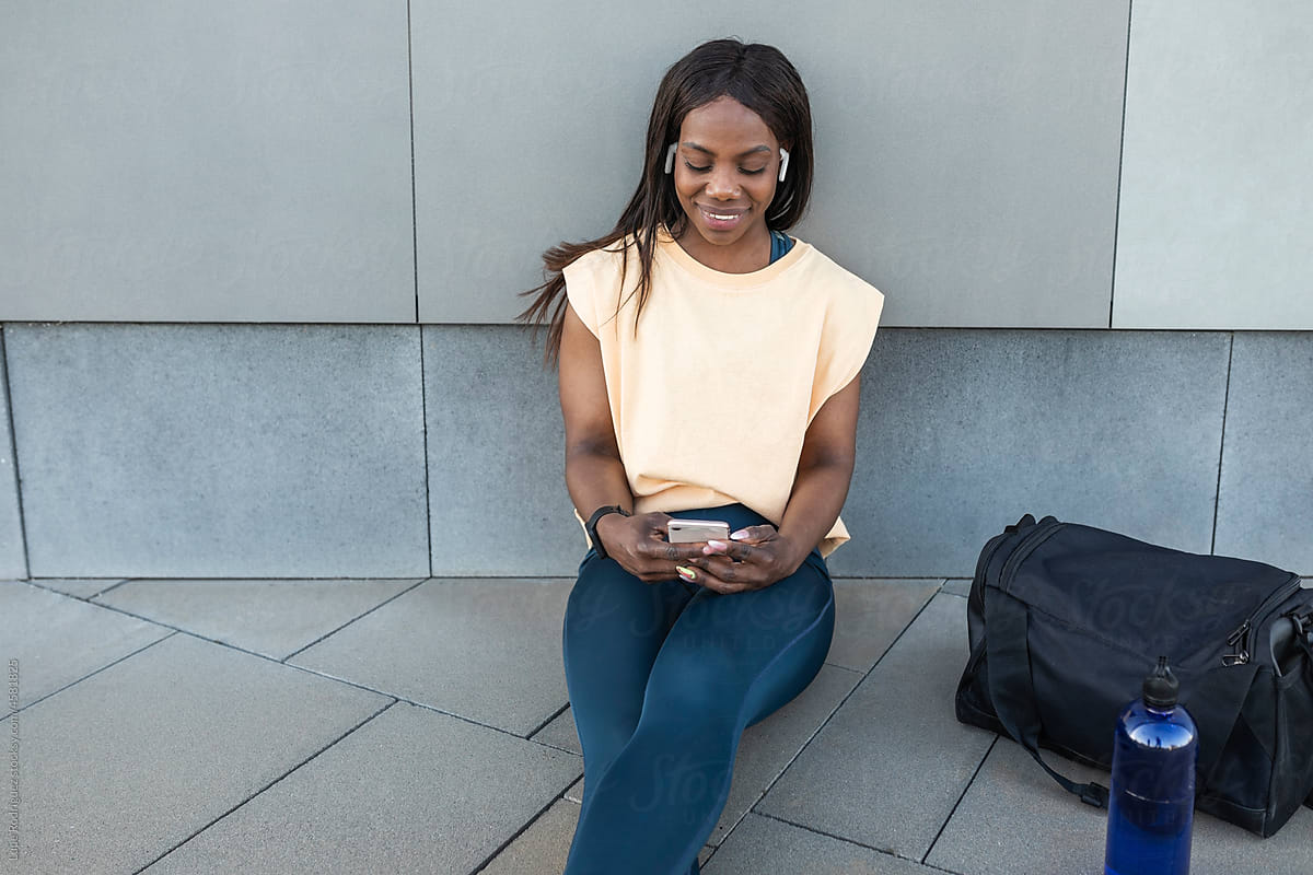 Black woman listening to music with mobile phone outdoors