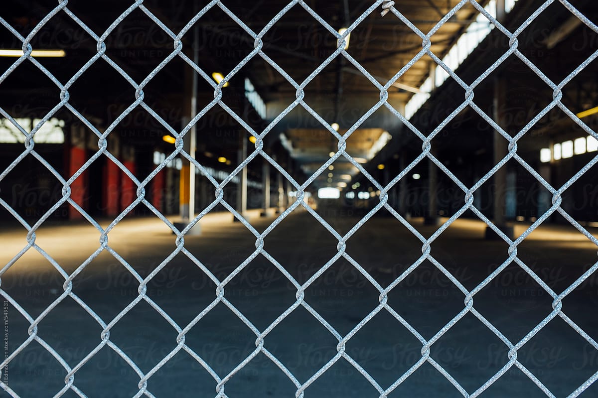 Chain-link fence in front of large warehouse