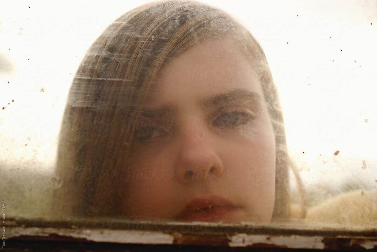 Teen looks through old glass window