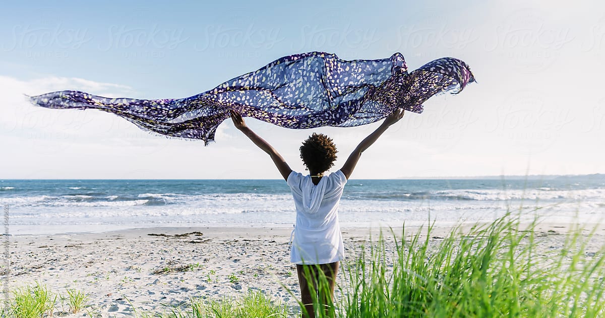 Young African American  girl at beach with scarf blowing in wind
