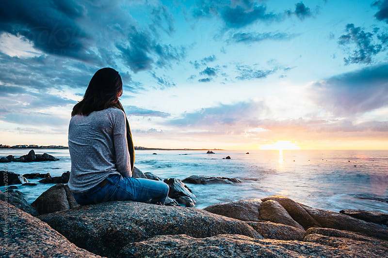 Woman Sitting On A Rock Enjoying A Beautiful Sunset View Over The Sea By Micky Wiswedel