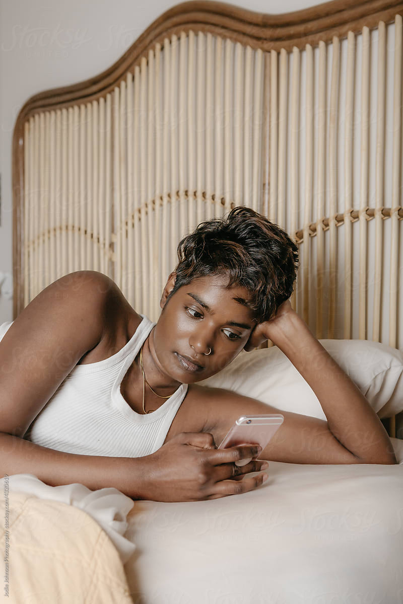 Black woman reading her phone in bed