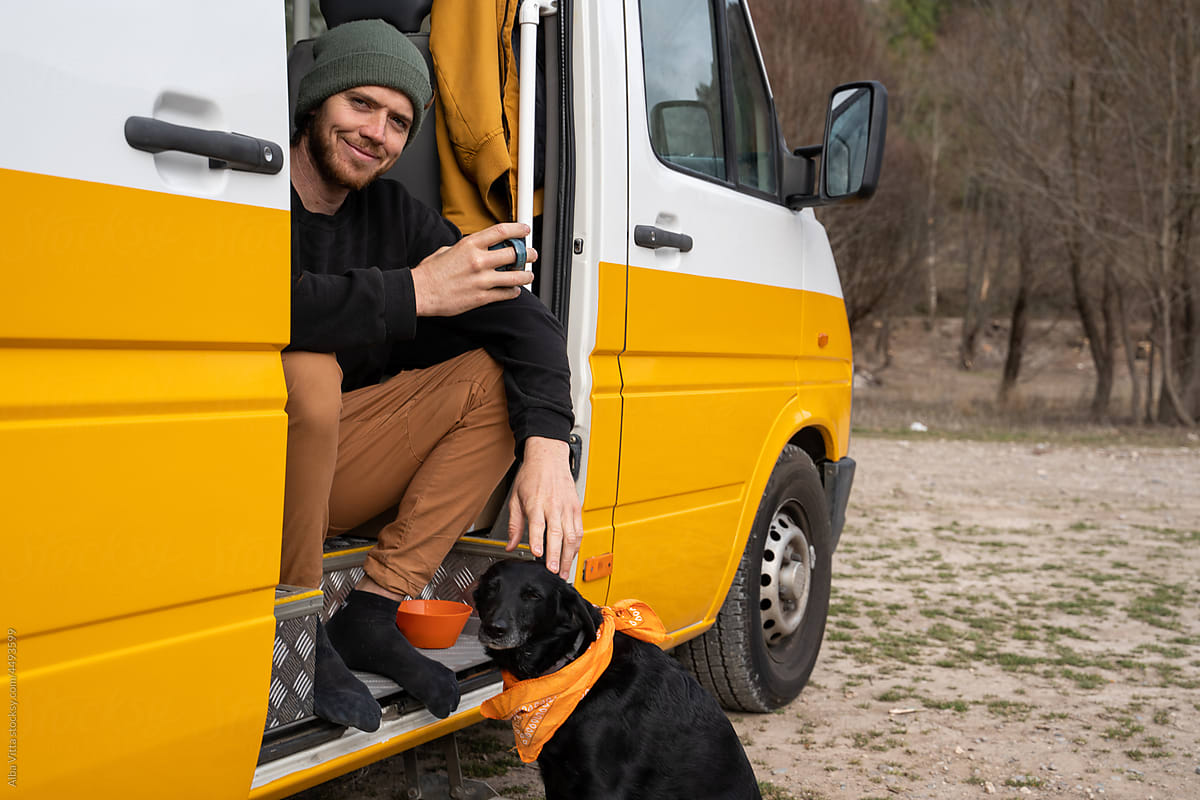Portrait of happy man exploring nature with his dog by camper van