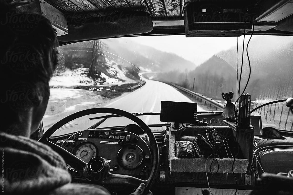 Man inside a truck driving along a road - black and white