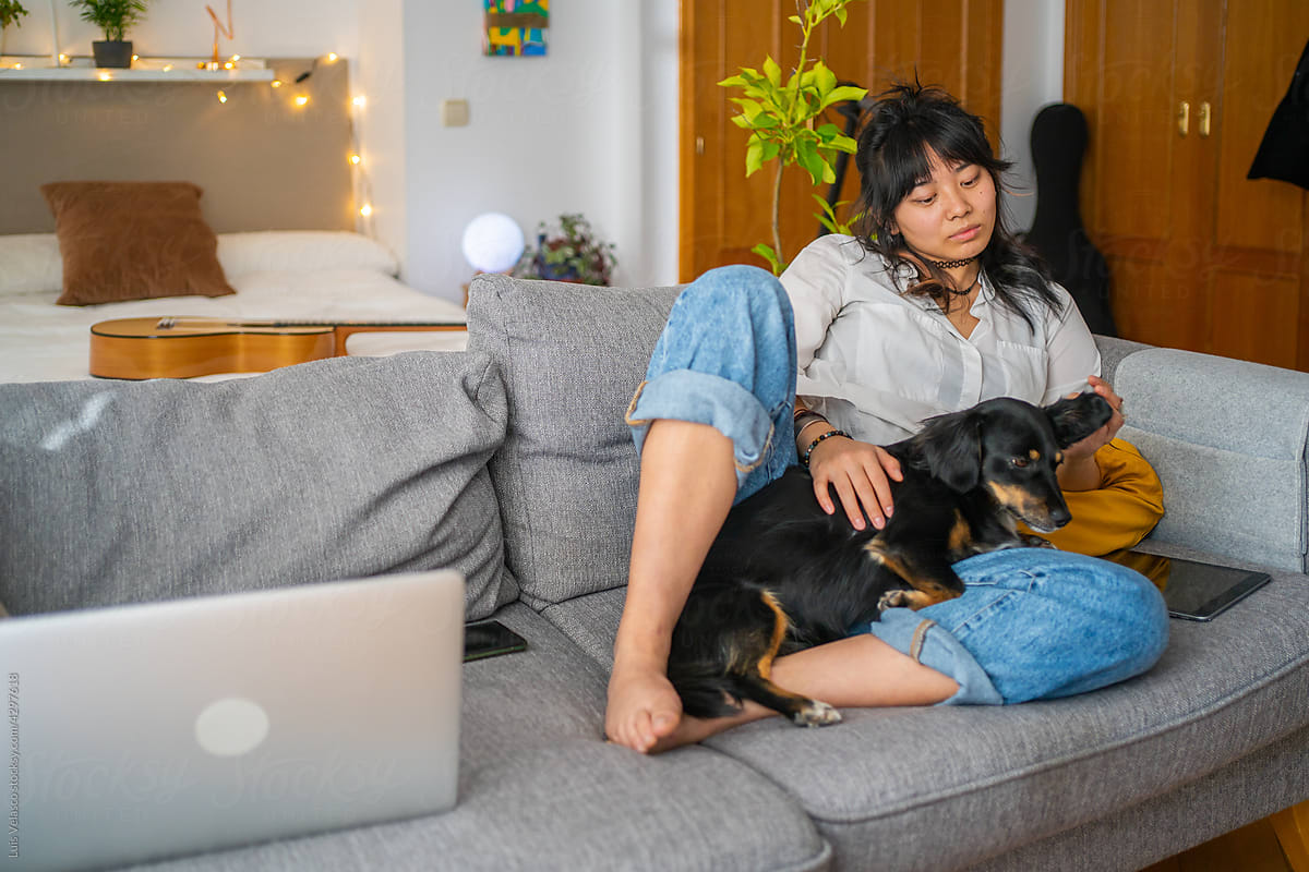 Relaxed Asian Girl Laying On The Couch With Her Dog.