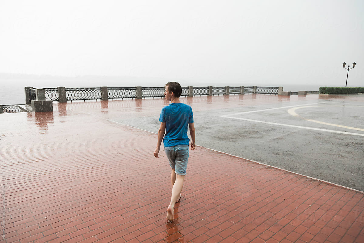 barefooted happy young man walking  under rain