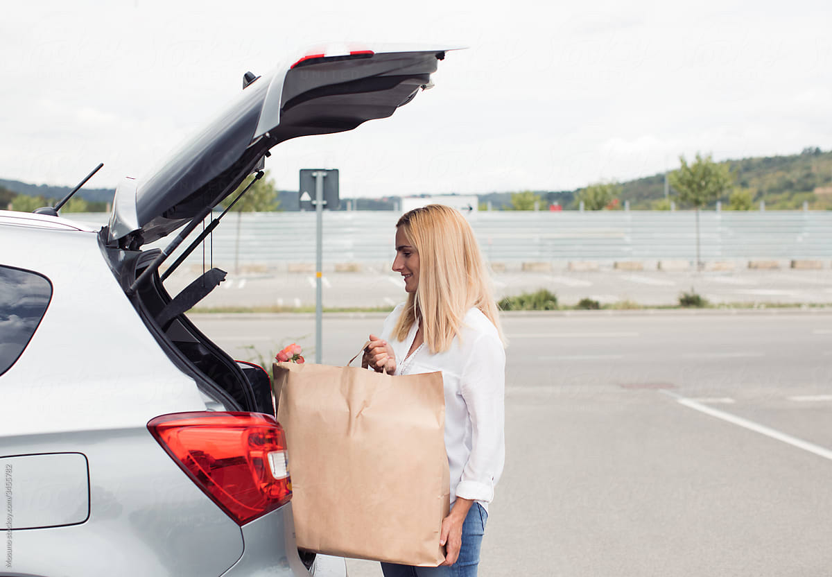 Woman putting Shopping back in the Car trunk