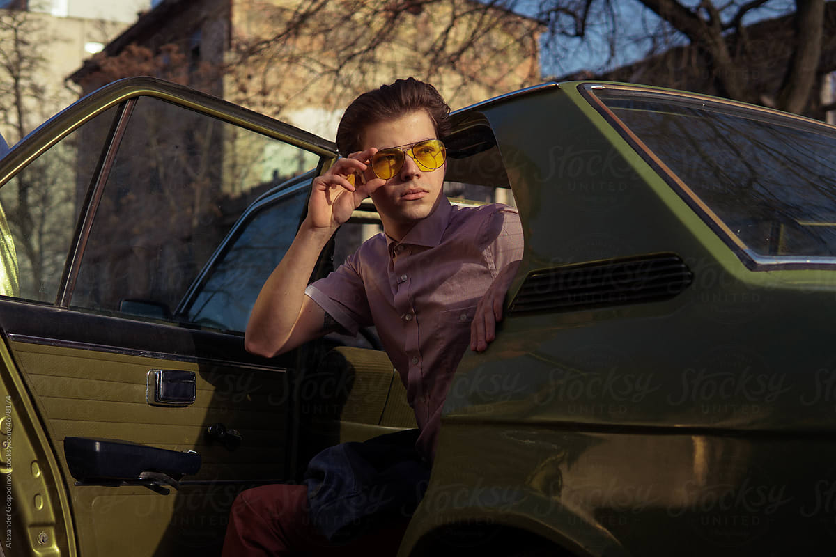 A stylish man inside a car with  sunlights