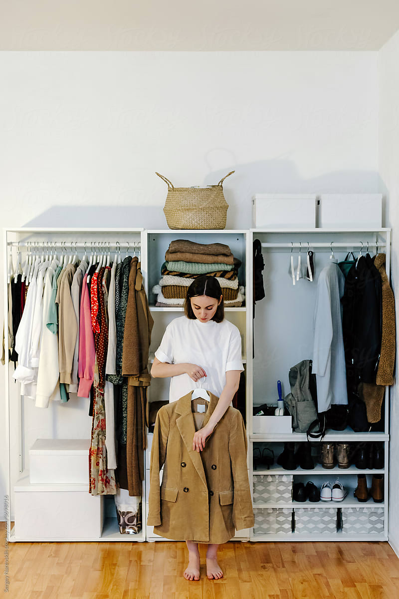 Woman standing with stylish jacket near wardrobe
