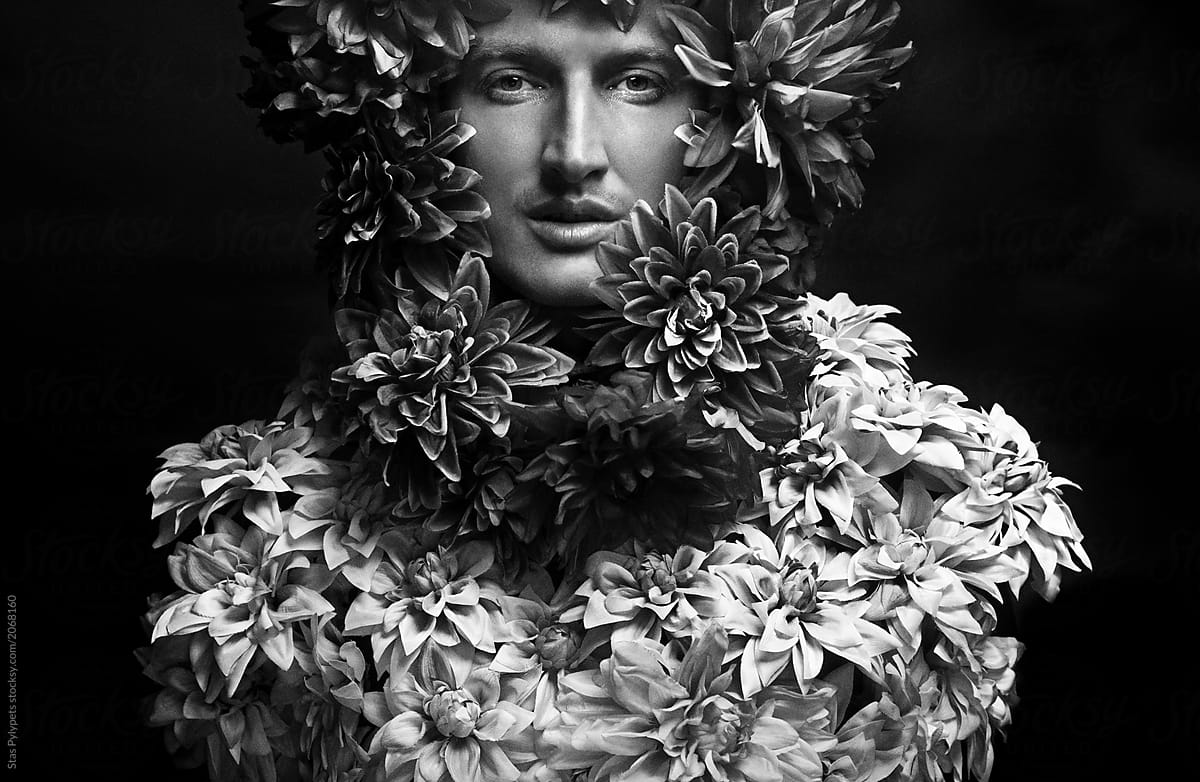 Fashionable portrait of a guy covered with flowers