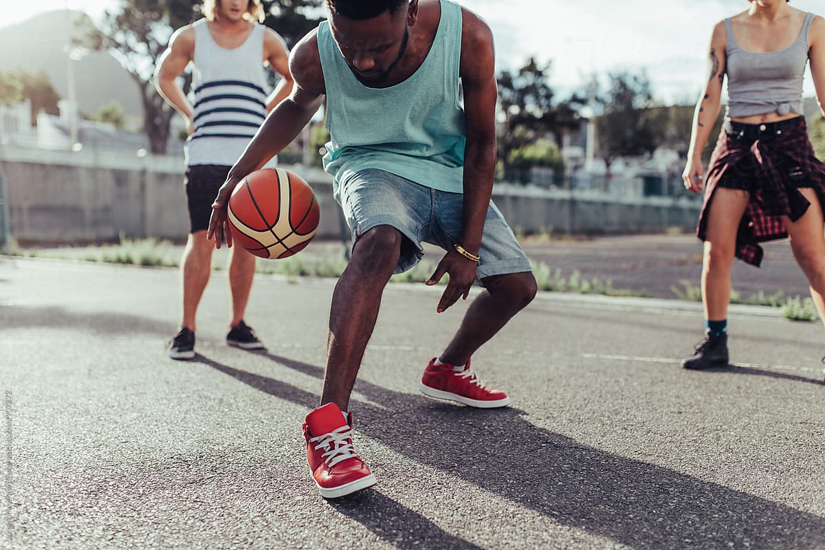 Young man playing basketball with group of friends