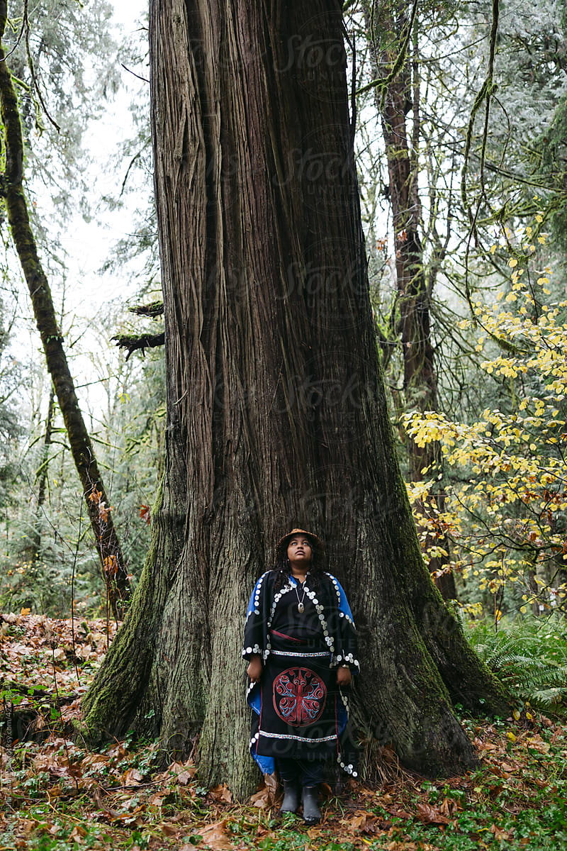 Young woman in regalia near old cedar