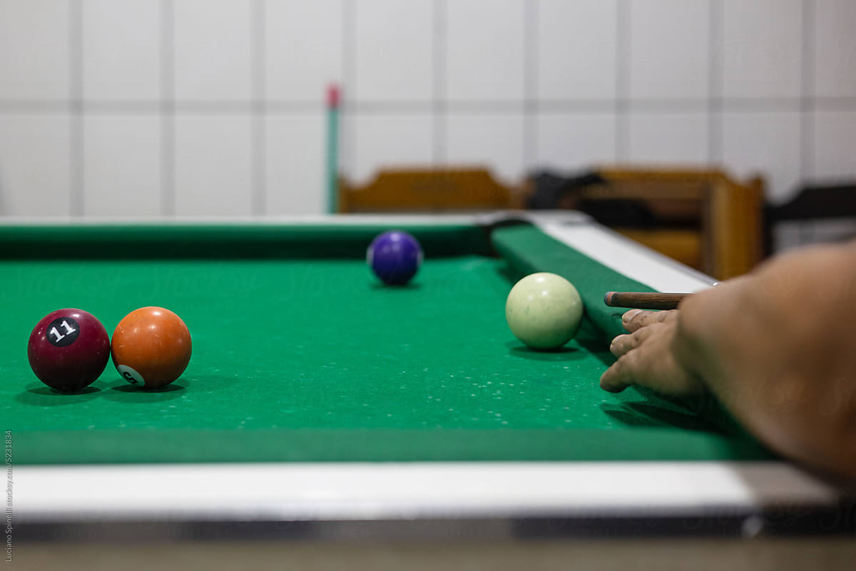 Anonymous men in Brazil playing pool billiard in bar and betting money