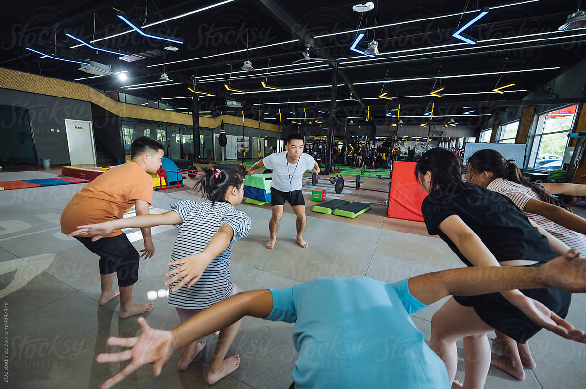 Asian coach instructing young kids