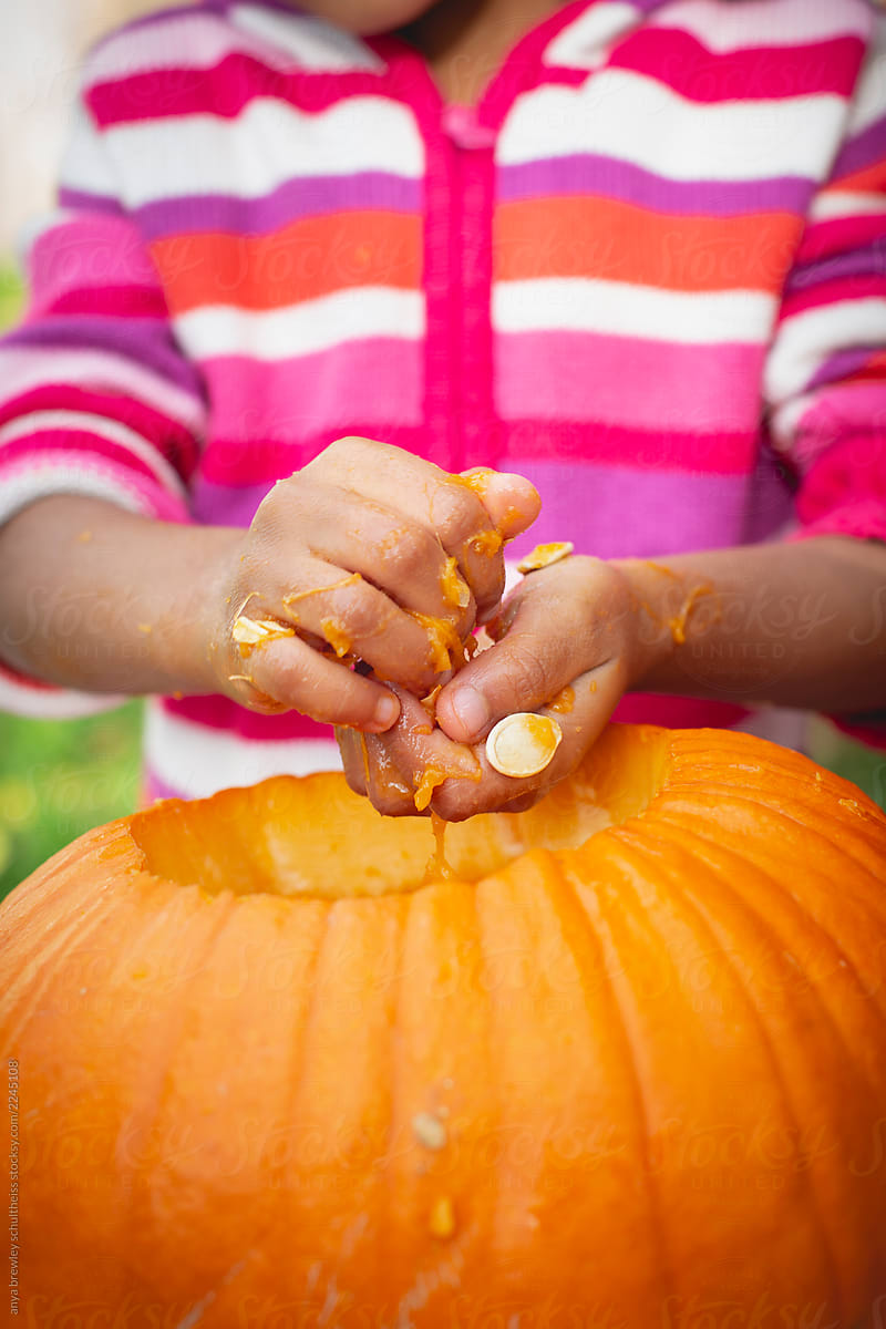Young child removing the seeds and pulp from a pumpkin