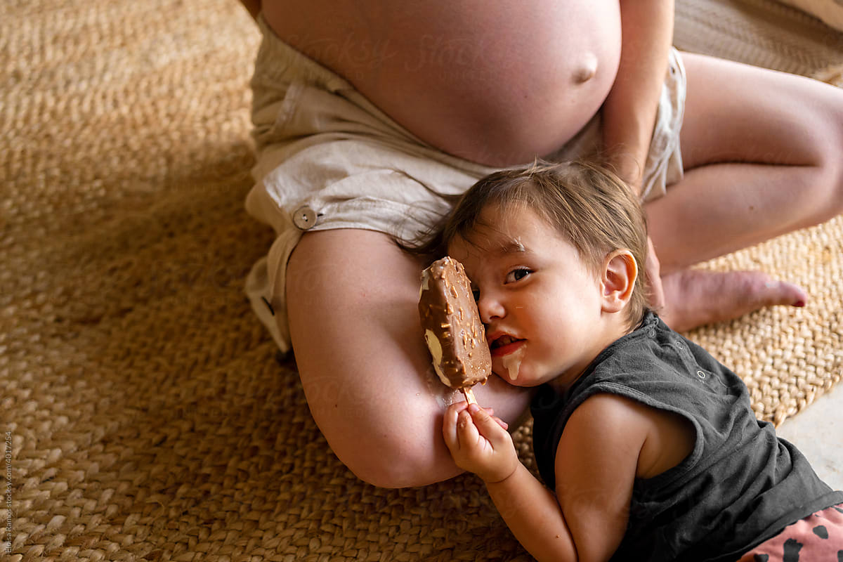 Funny boy with ice cream lying on his pregnant mom