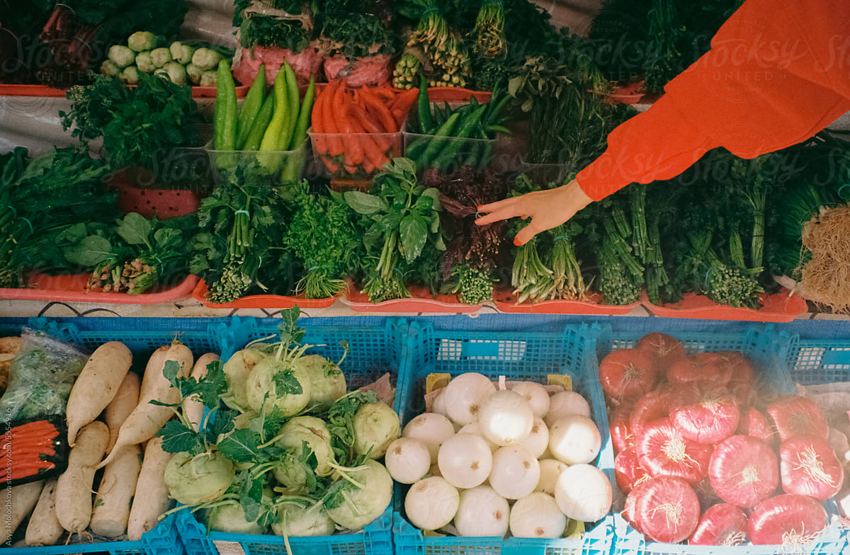 Woman choosing vegetables and greens at the market