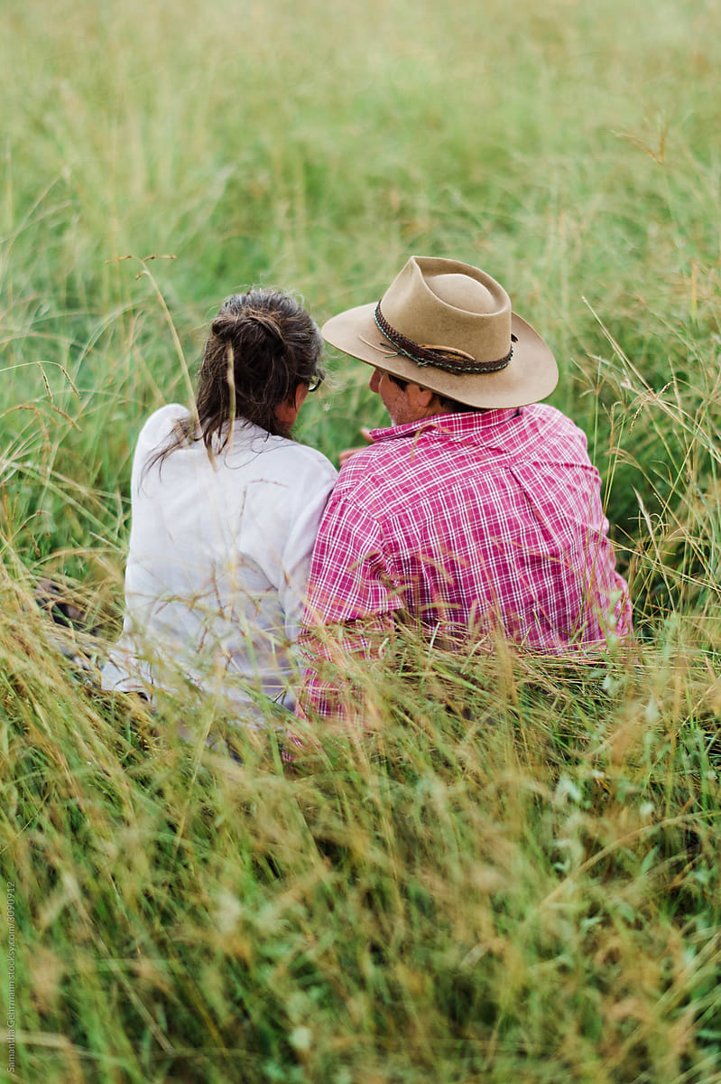 Couple sitting in grass from behind