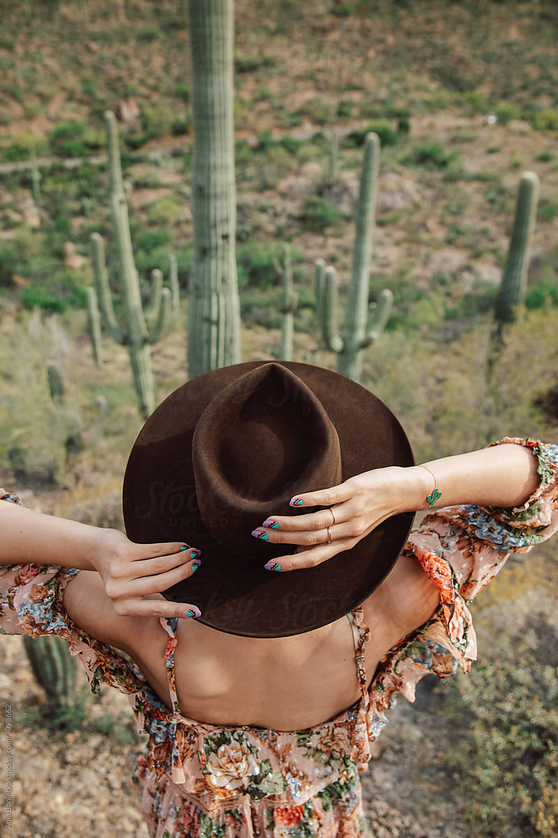 Top view of a stylish cowgirl looking down at saguaro cacti.