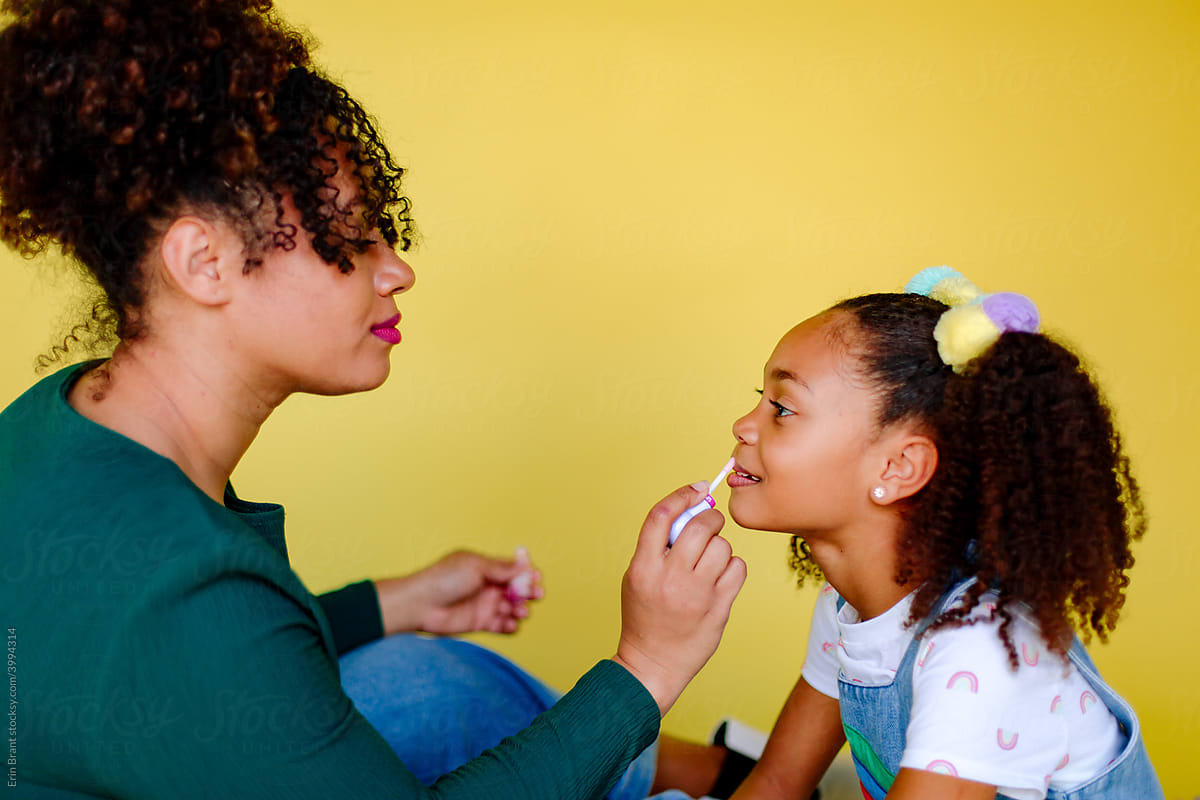 Mother applying lipgloss on daughter
