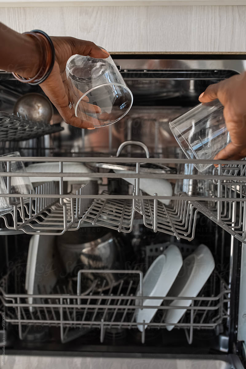 Crop black housekeeper taking glasses from dishwasher