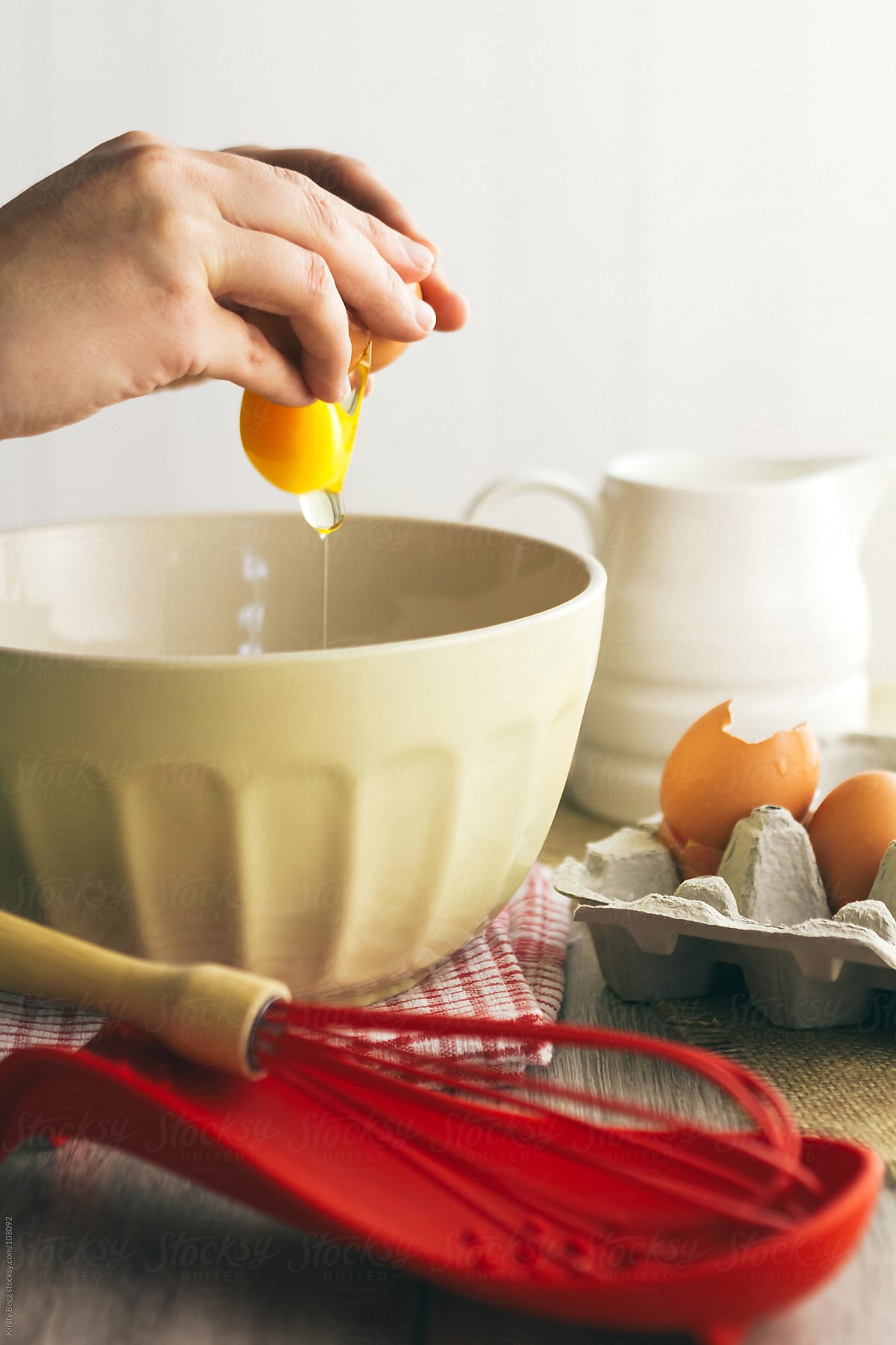 Woman cracking egg into mixing bowl