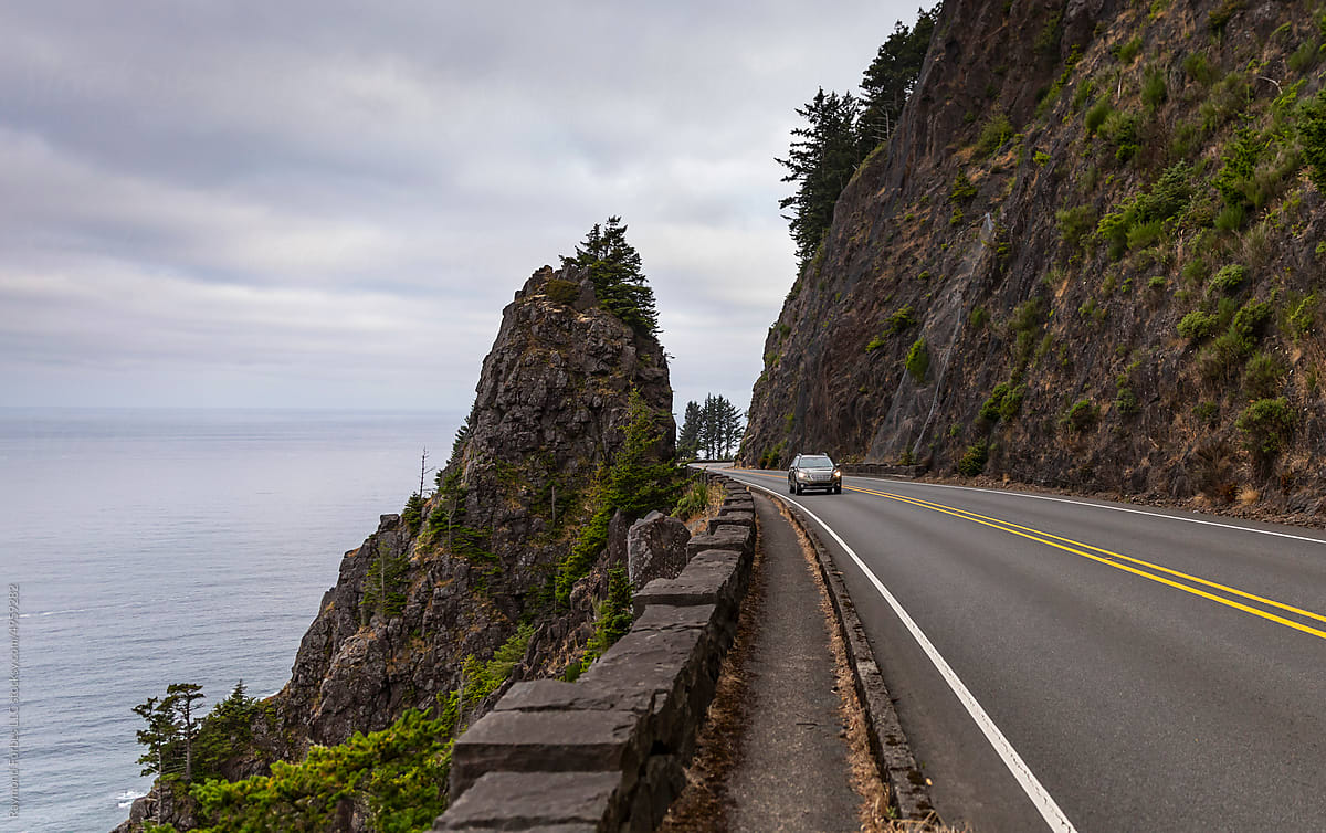 Lone car on Rugged Oregon Coast landscape with rock formation