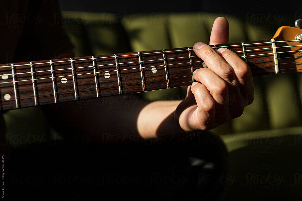 Close up of a male hand on the frets of a guitar
