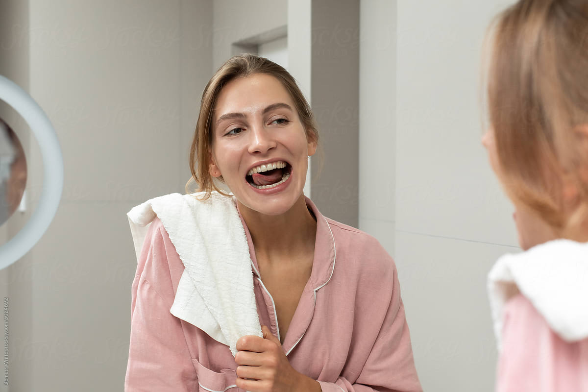 Woman smiling into mirror in bathroom