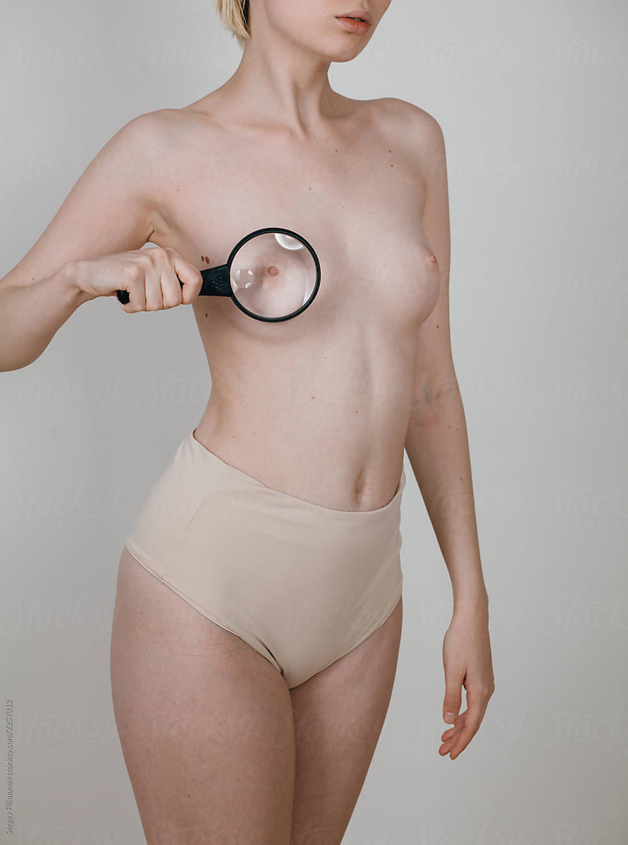 Crop nude woman with magnifying glass against nipple