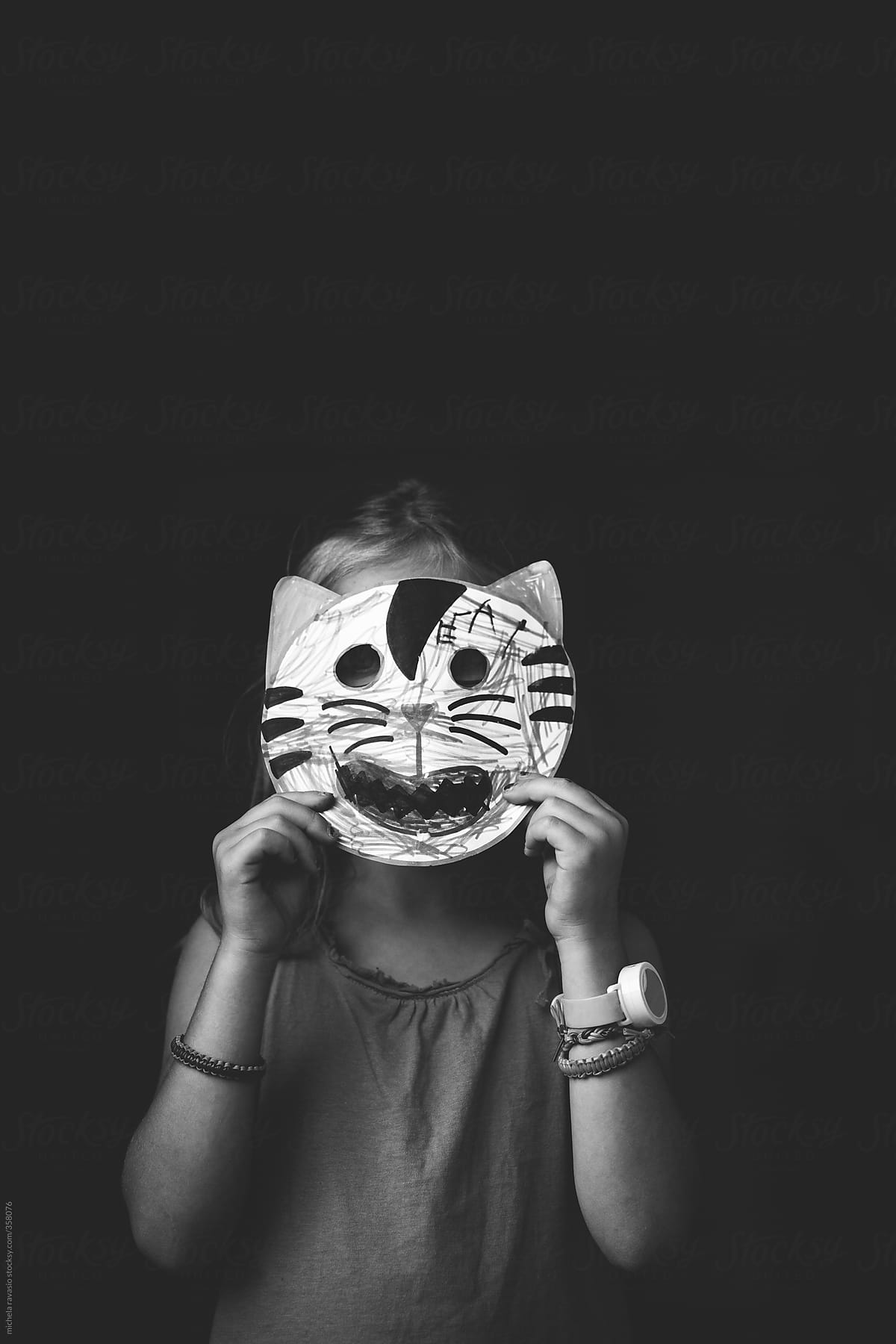 Little girl holding a paper mask made ​​by her