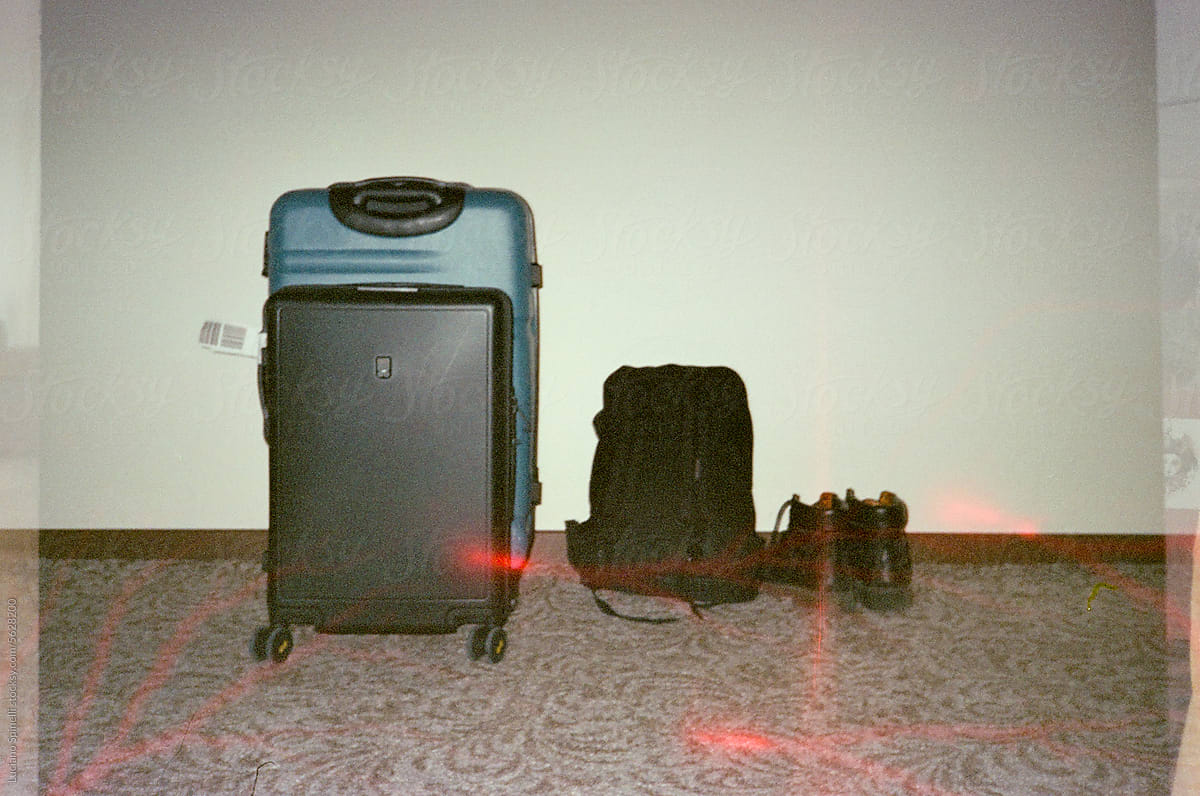 Travel baggage: suitcase, bag and backpack next to pair of shoes