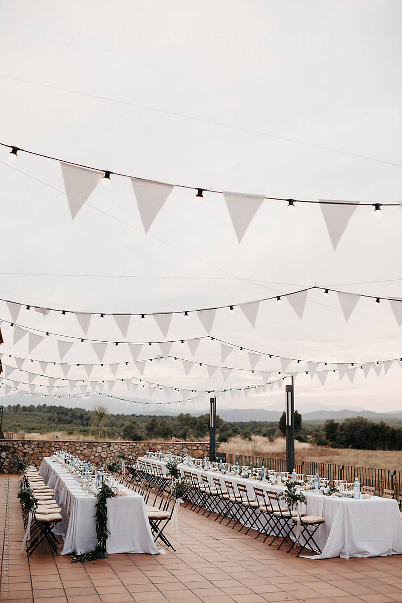 Outdoor wedding reception with white bunting flags and string lights