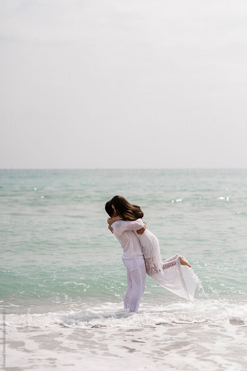 Romantic newlyweds hugging in sea waves