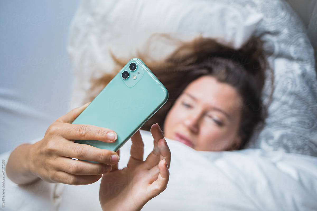 Woman in bed on the phone texting