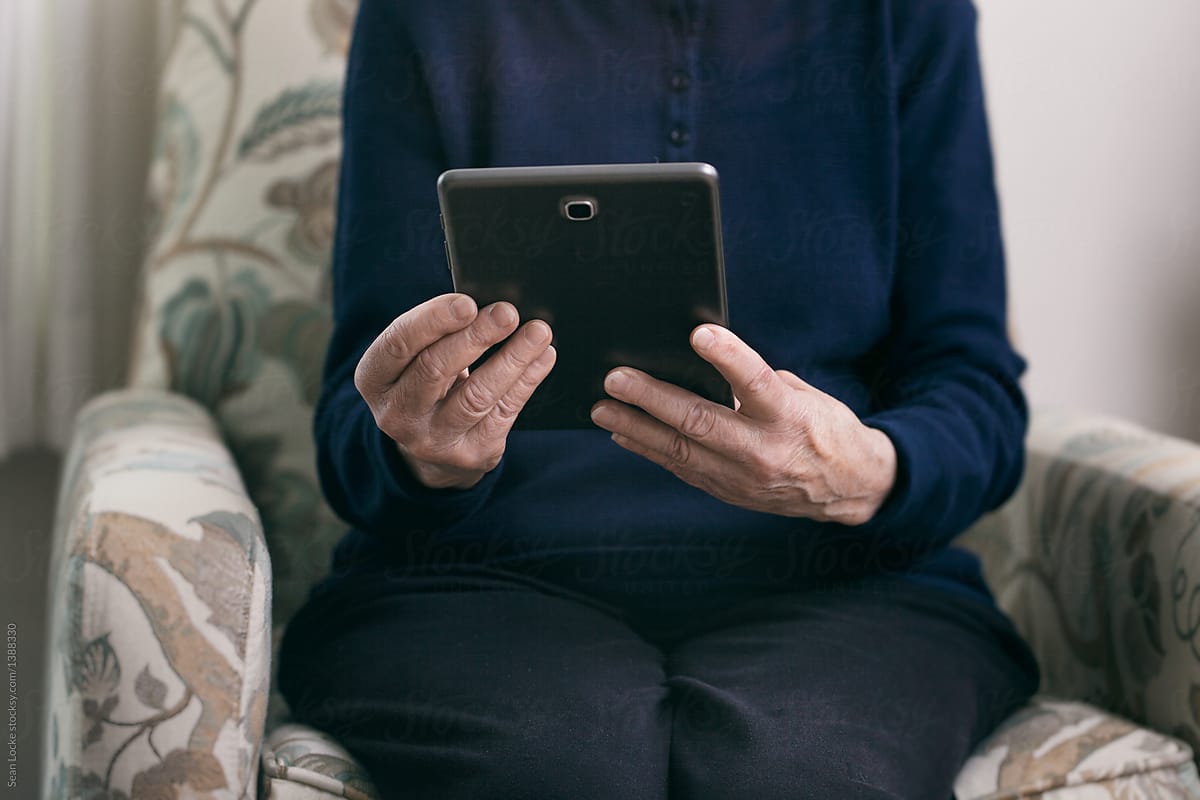 Senior: Woman Sits In Chair Using Digital Tablet