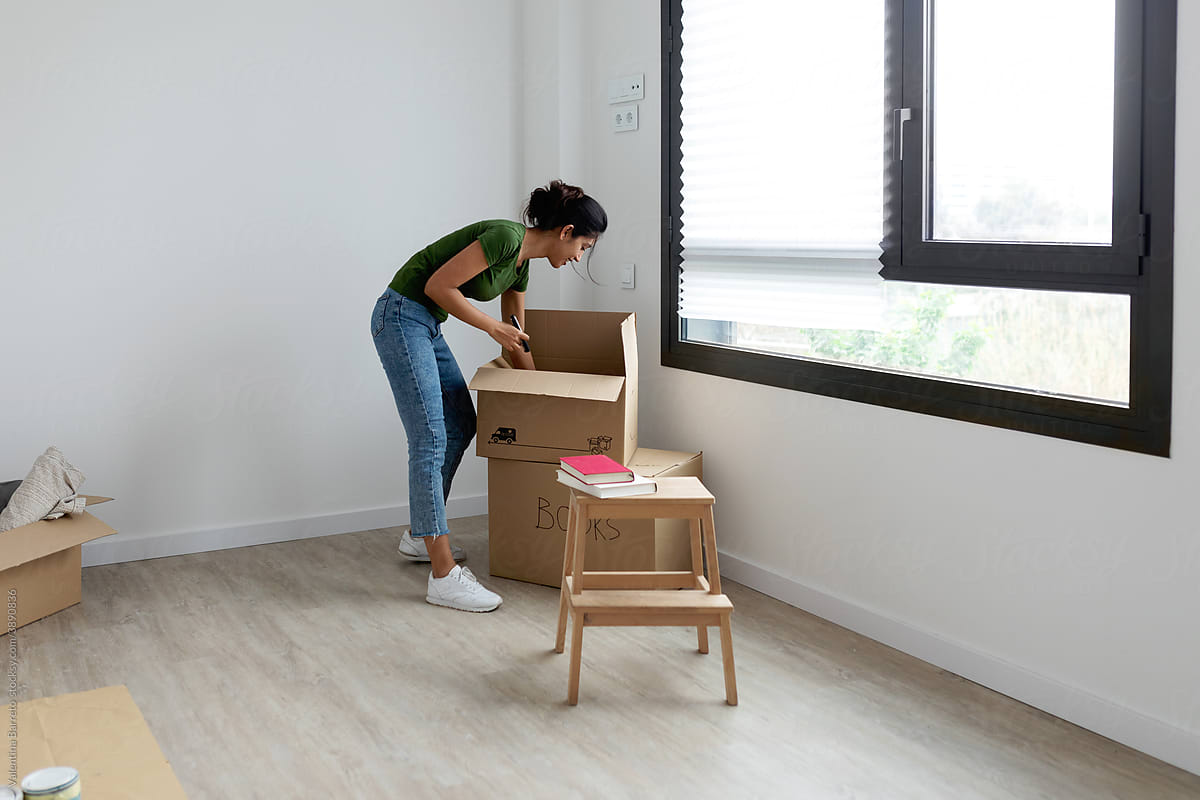 Woman unpacking moving boxes with books