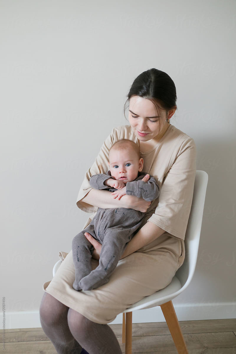 mom holds the baby in her arms and sits on a chair