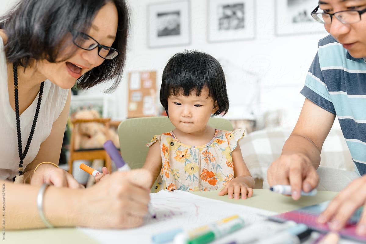 Little girl drawing pictures with her parents