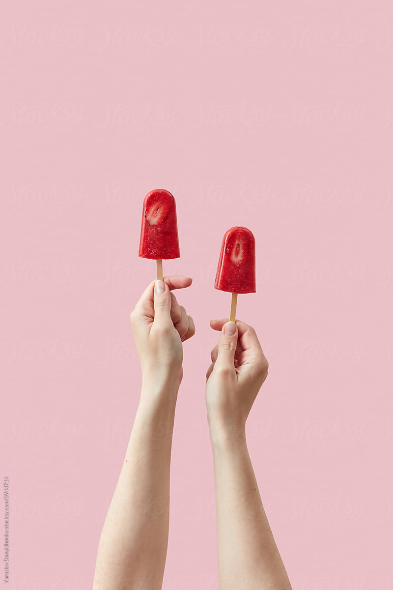 Woman holding strawberry ice creams on sticks