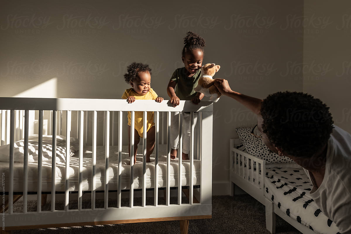 Father plays with daughters in crib