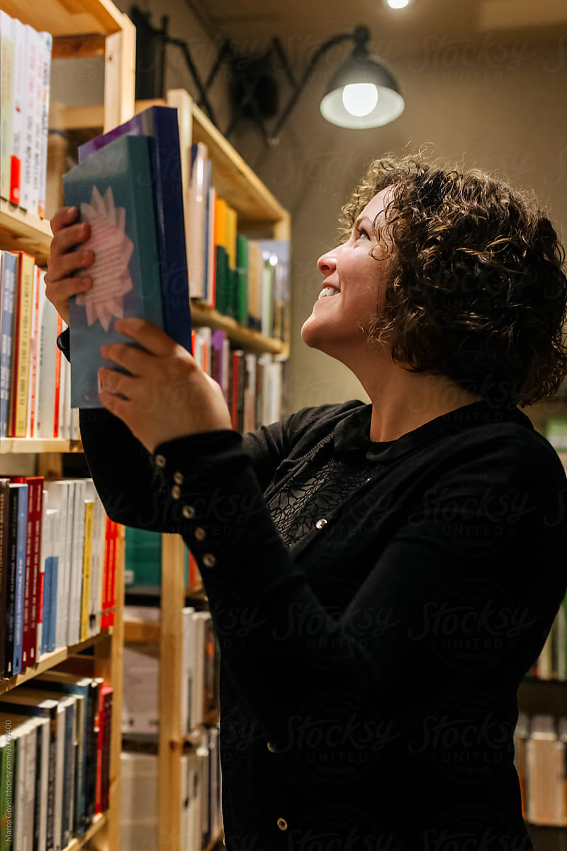 Female bookseller placing books on the bookshelf
