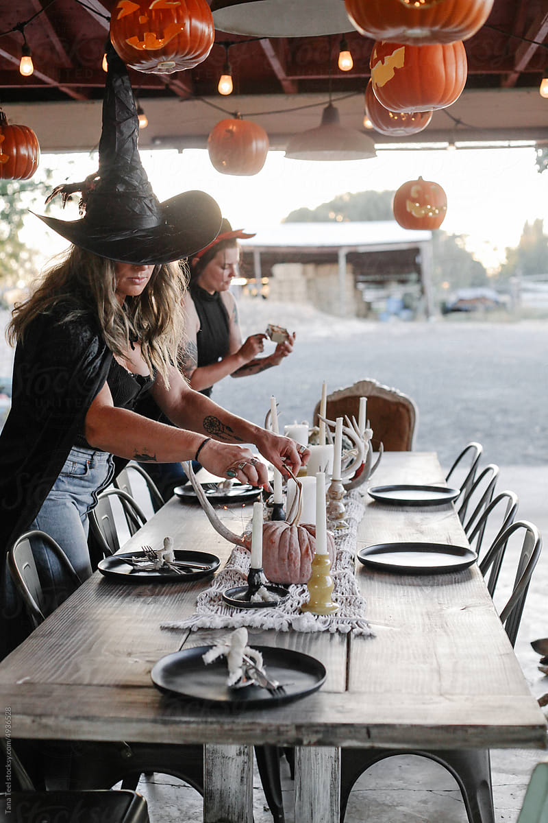 costumed friends decorate outdoor table for halloween