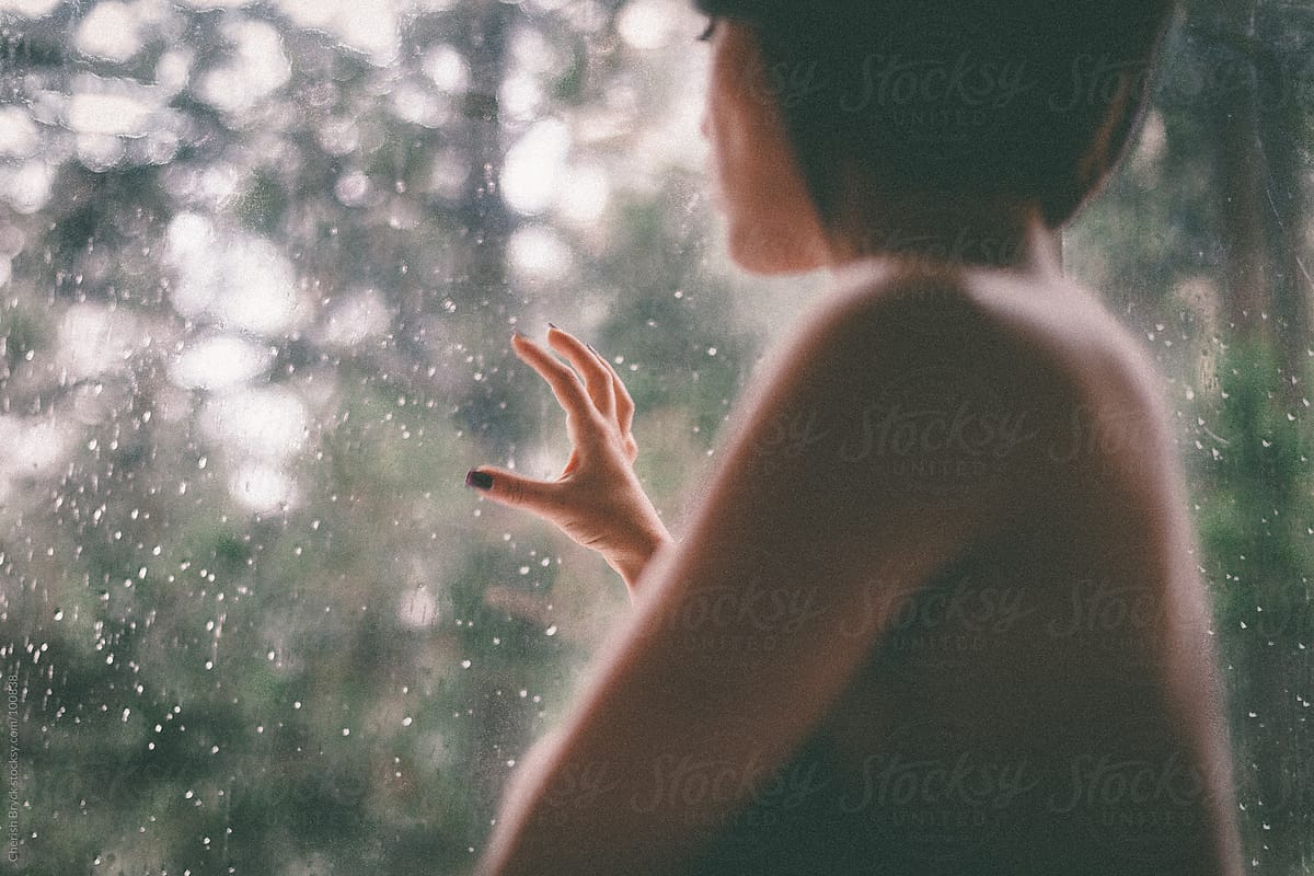 Woman views forest through the window.