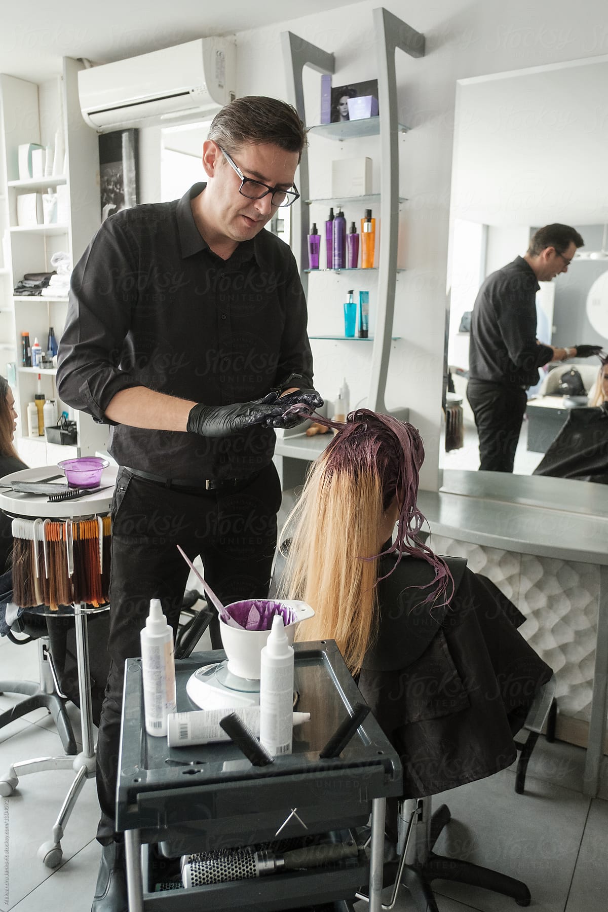 Male Hairdresser Working With A Female Customer With Blond Hair