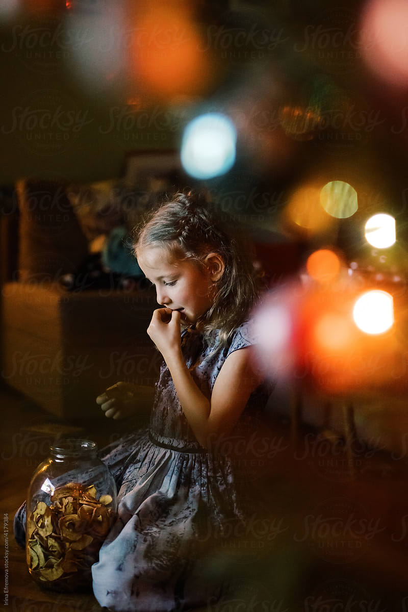 Little girl watching TV by a Christmas tree