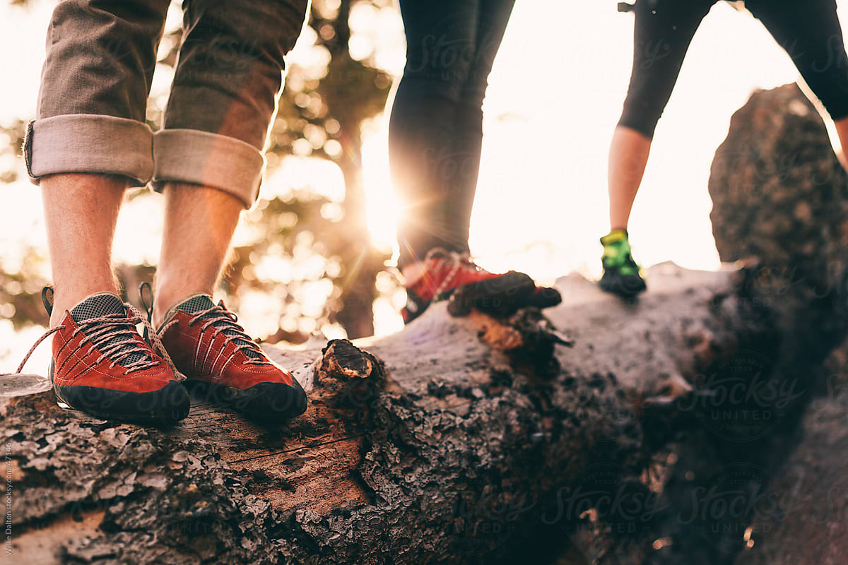 Three People Wearing Rock Climbing Shoes Stand on a Log