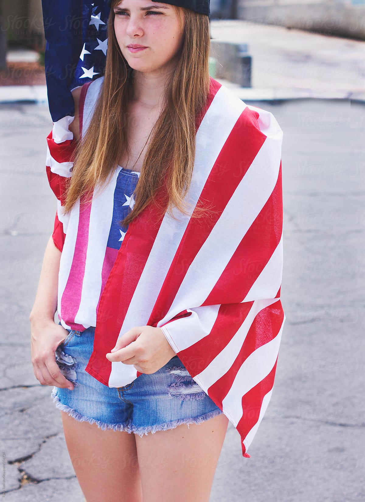 Teenager in shorts and flag shirt wrapped in American flag