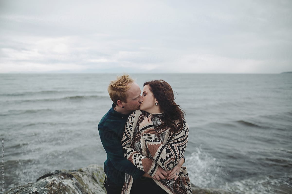 Young, stylish couple close together outside in winter kissing