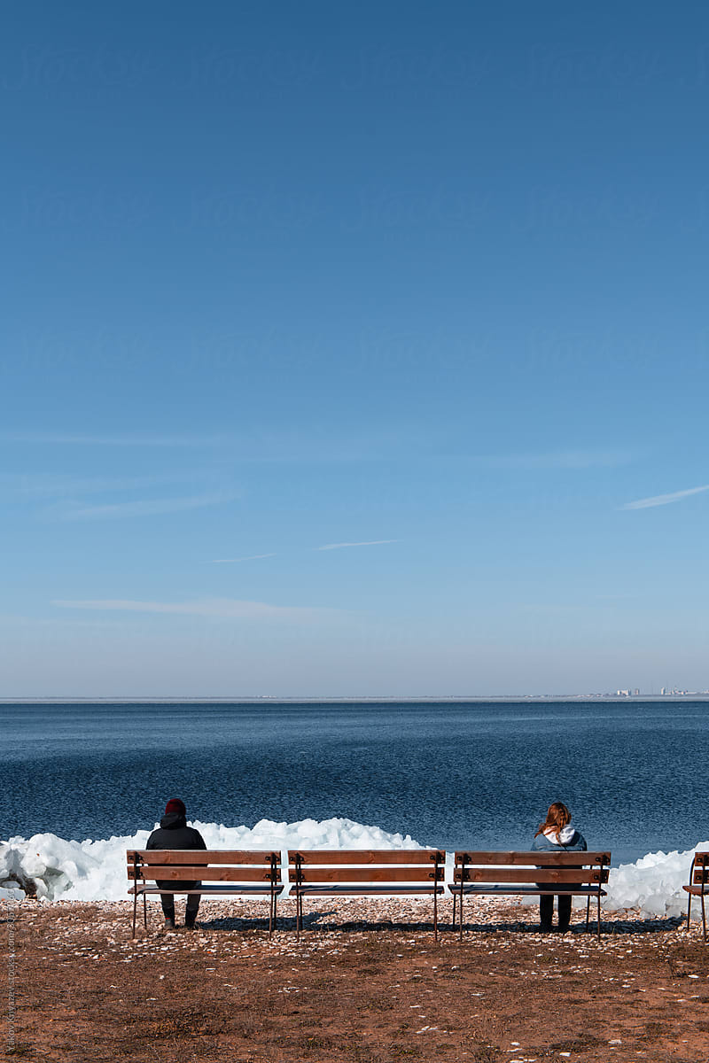 Man and woman on the bench sit far from each other not to get contacted